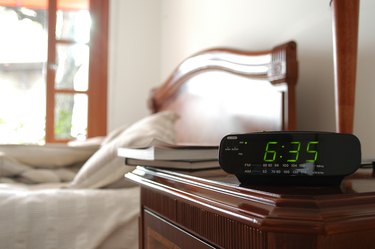 An alarm clock with time of 635 over a blurred bed