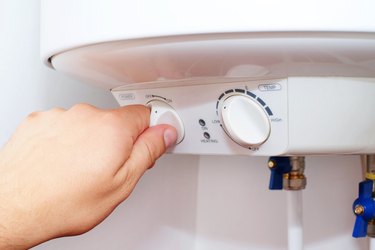 Man turns on the switch on control panel of home electric water heater (boiler).