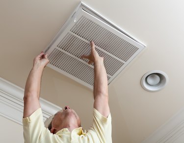 Low Angle View Of Senior Man Adjusting Air Duct