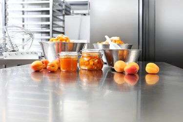 Jam from apricots in a glass jar on a polished stainless steel surface in pastry worktop