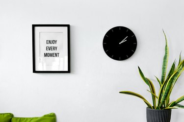 White wall decoration with a picture frame, clock and plants