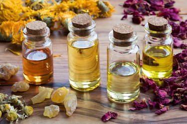 Bottles of essential oil with dried rose petals, chamomile, calendula and frankincense