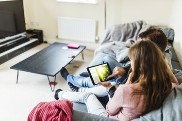 Man and woman using digital tablet to set the temperature.