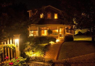 Seaside cottage with screened porch, brick walkway and a American flag, all illuminated at night