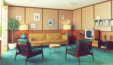 1970s living room with blue carpet, yellow couch, and paneling on the walls