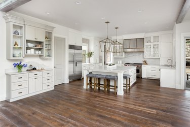 beautiful kitchen in new luxury home with island, pendant lights, and laminate floors