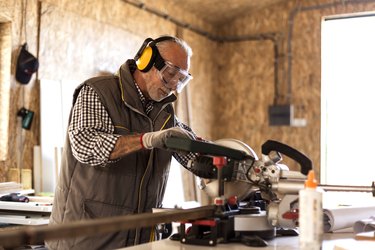 Mature carpenter using circular saw in his workshop