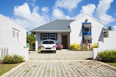 Car in a driveway at a white Caribbean style home