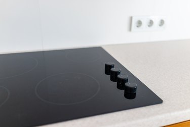 Closeup and knobs on modern luxury electric cook stove top stovetop cooktop with glass reflection and circles background in empty home
