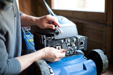 A man repairing a petrol lawn mower