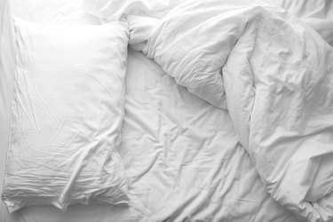 Messy bed. White pillow with blanket on bed unmade. Concept of relaxing after morning.