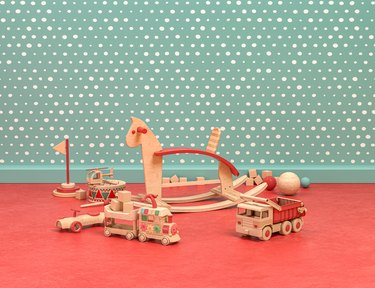 Wood and plastic vintage style playroom with cockhorse and toys on green and red background, 3d Rendering