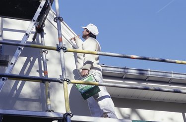 Man on scaffolding painting house, low angle