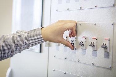 engineer switches on circuit breaker in electric switchboard close-up. Supply electricity concept. electrician's hand against electrical panel background.