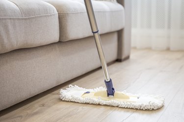 Modern white mop being used for cleaning a wooden floor