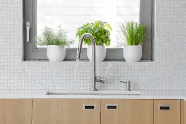 Modern kitchen stainless steel faucet with water running into sink.