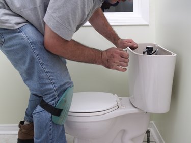 Plumber at work repearing toilet