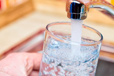 Filling up a glass with water from kitchen tap POV