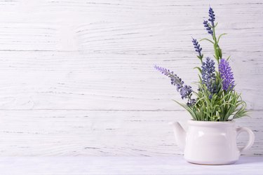 Lavender flowers in watering can, wooden background, copy space