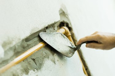 Man applying putty to pipe, cropped view of hand