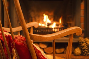 Wooden rocking chair and the fireplace interior at home. Winter weekend. Evening on Christmas holiday. Interior design.