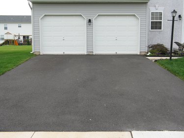 A double garage with white doors at the end of a driveway