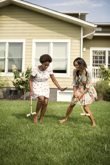 Friends playing croquet in backyard.