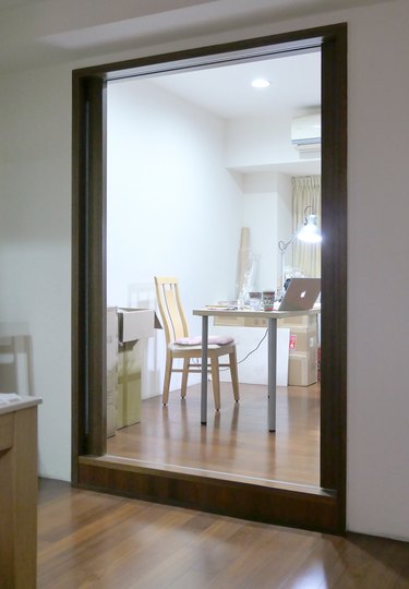 Wood doorway to sparse room with a desk, boxes, and chair