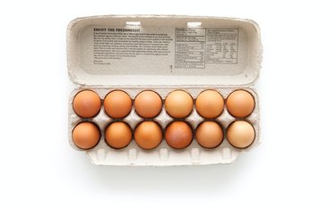 brown eggs in egg carton on white background