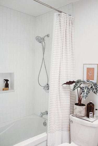 Polished chrome shower fixtures in white tile shower in modern bathroom