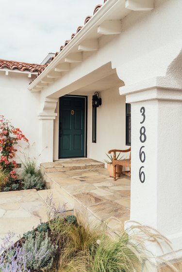 A white Mediterranean-style home entrance with black address numbers