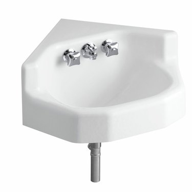 White cast iron wall mount corner bathroom sink with silver fixtures