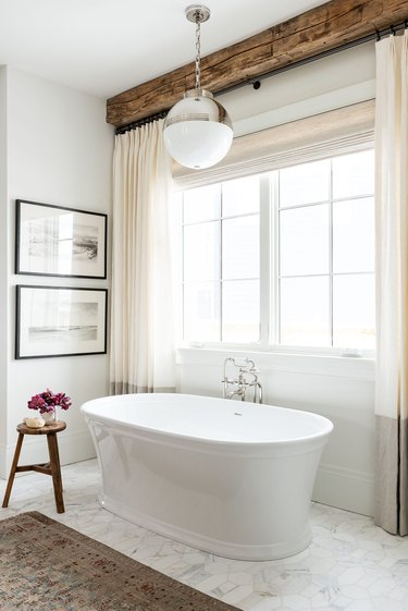 freestanding tub with traditional bath fixtures and wood beam ceilings