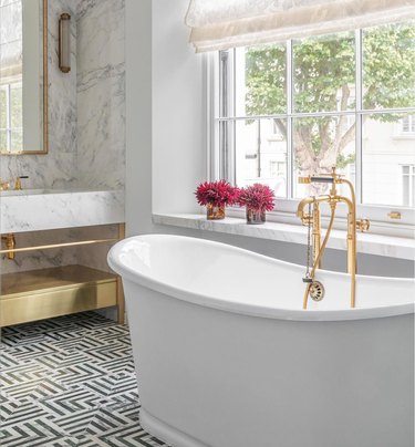 glamorous marble bathroom with freestanding tub and brass fixtures