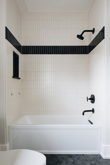 modern tub and shower fixtures in black and white bathroom