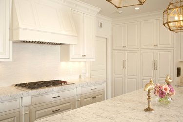 all white kitchen with marble countertops and raised panel cabinetry