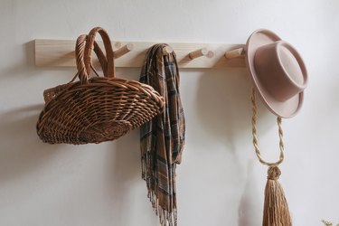 DIY wooden peg rail on wall with baskets, scarf and hat hanging from it