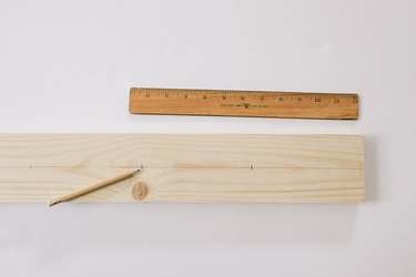Line drawn down center of wood board with marks for peg spacing