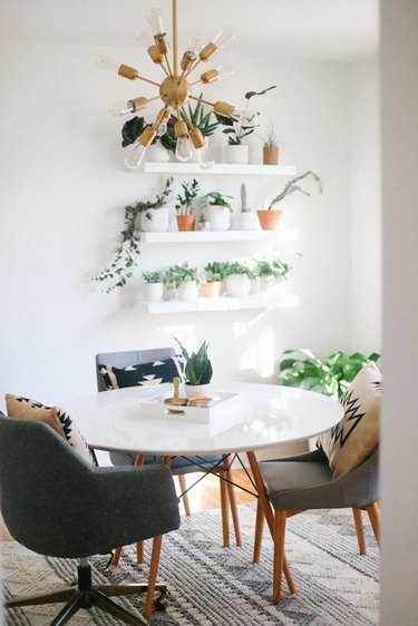 Midcentury modern home office with white open shelves, plants, and large table