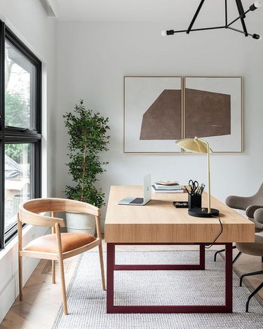 white modern home office with  large desk in the center and wall art hanging above