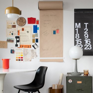 modern home office with black office chair and colorful papers and calendar on the wall