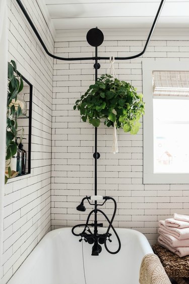 Black plumbing fixtures with clawfoot tub and subway tile