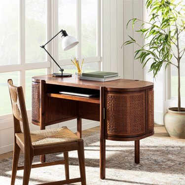 cane desk with chair near windows and plant