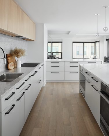 Modern cookspace with white flat panel kitchen cabinets and black pulls