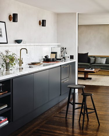 Modern cookspace with black flat panel kitchen cabinets and marble countertop