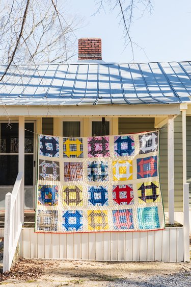 multicolored quilt hanging in front of a house