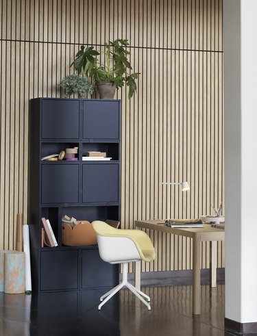 blue cubby style bookcase in a wood paneled office with a scandinavian style desk and chair