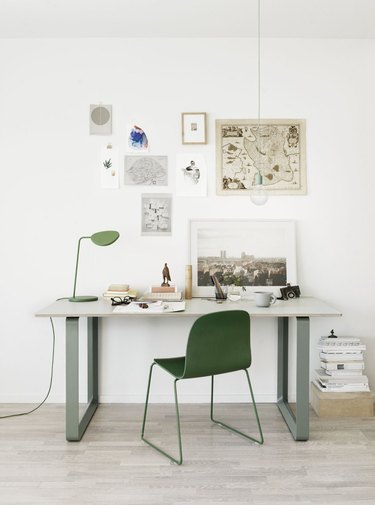 white Scandinavian home office with sage green and white desk, green chair and art on the walls