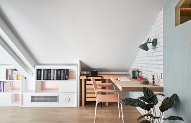 Scandinavian home office in the attic with brick wall and white storage unit