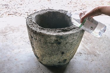 Pouring 1/2 cup of vinegar and gallon of water into hypertufa pot